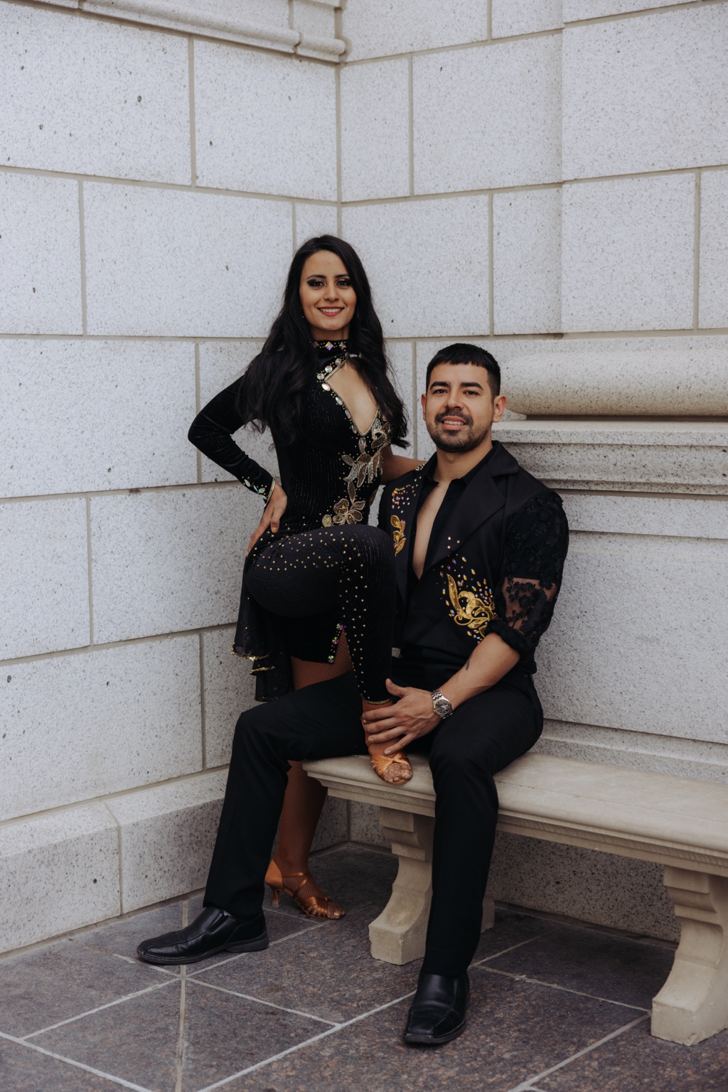 A FÉNIX Bachata couple in black and gold costumes